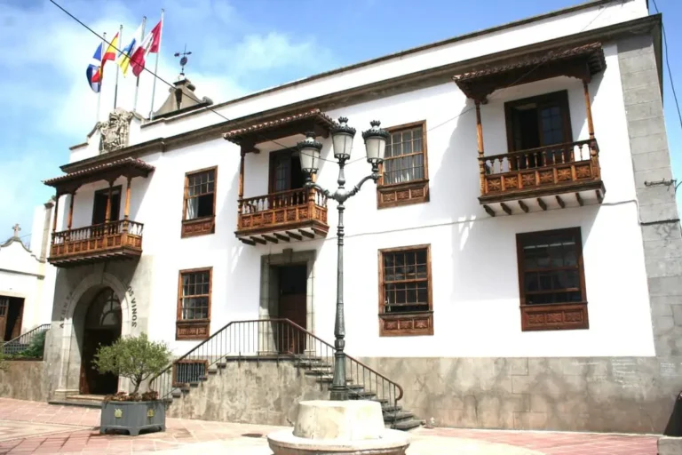 Fachada blanca del Ayuntamiento de Icod de los Vinos con balcones canarios de madera, banderas y una farola en la plaza