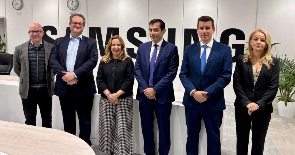 Seis profesionales trajeados posan juntos en una sala de reuniones ante el logotipo de Samsung en la pared